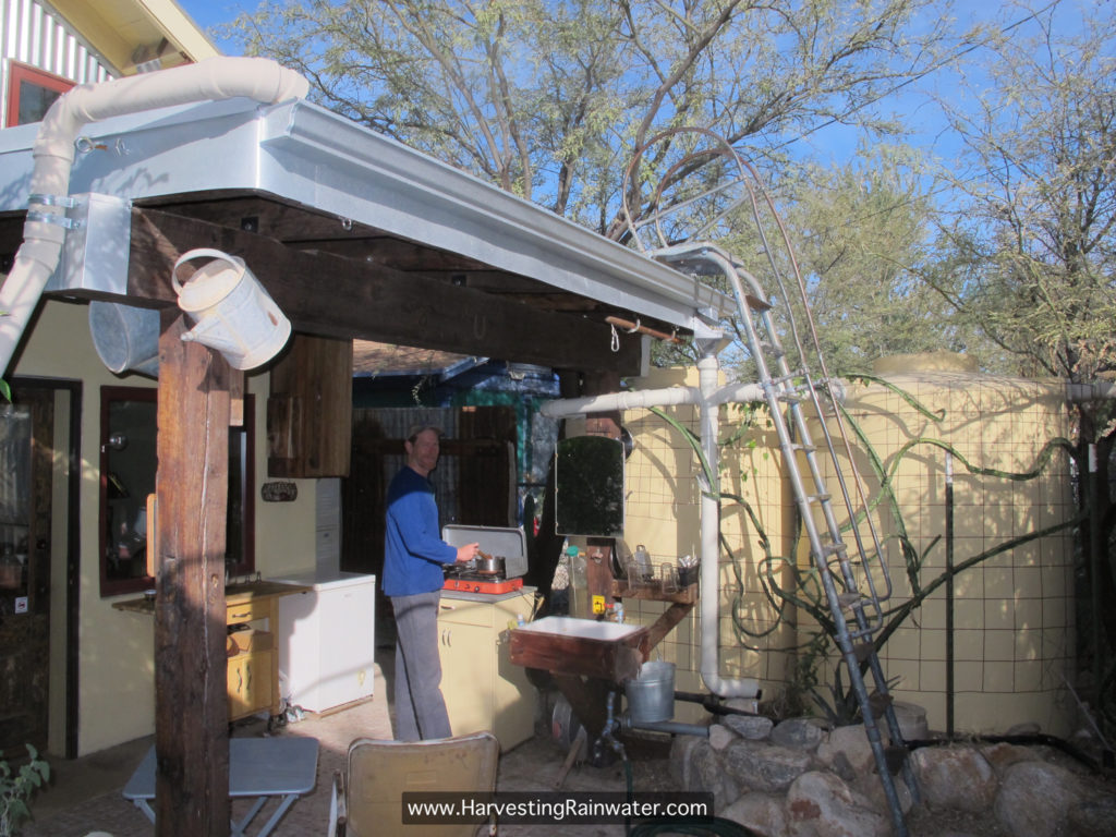 Figure 12. Garottage outdoor kitchen under east porch roof, and two 1,000-gallon rainwater tanks. Rainwater collected from 450-ft2 roof area provides all the water needed for the garottage in Tucson, Arizona, where 11 inches of rain falls in an average year. Water is distributed with a gravity-fed system—no pumps. 